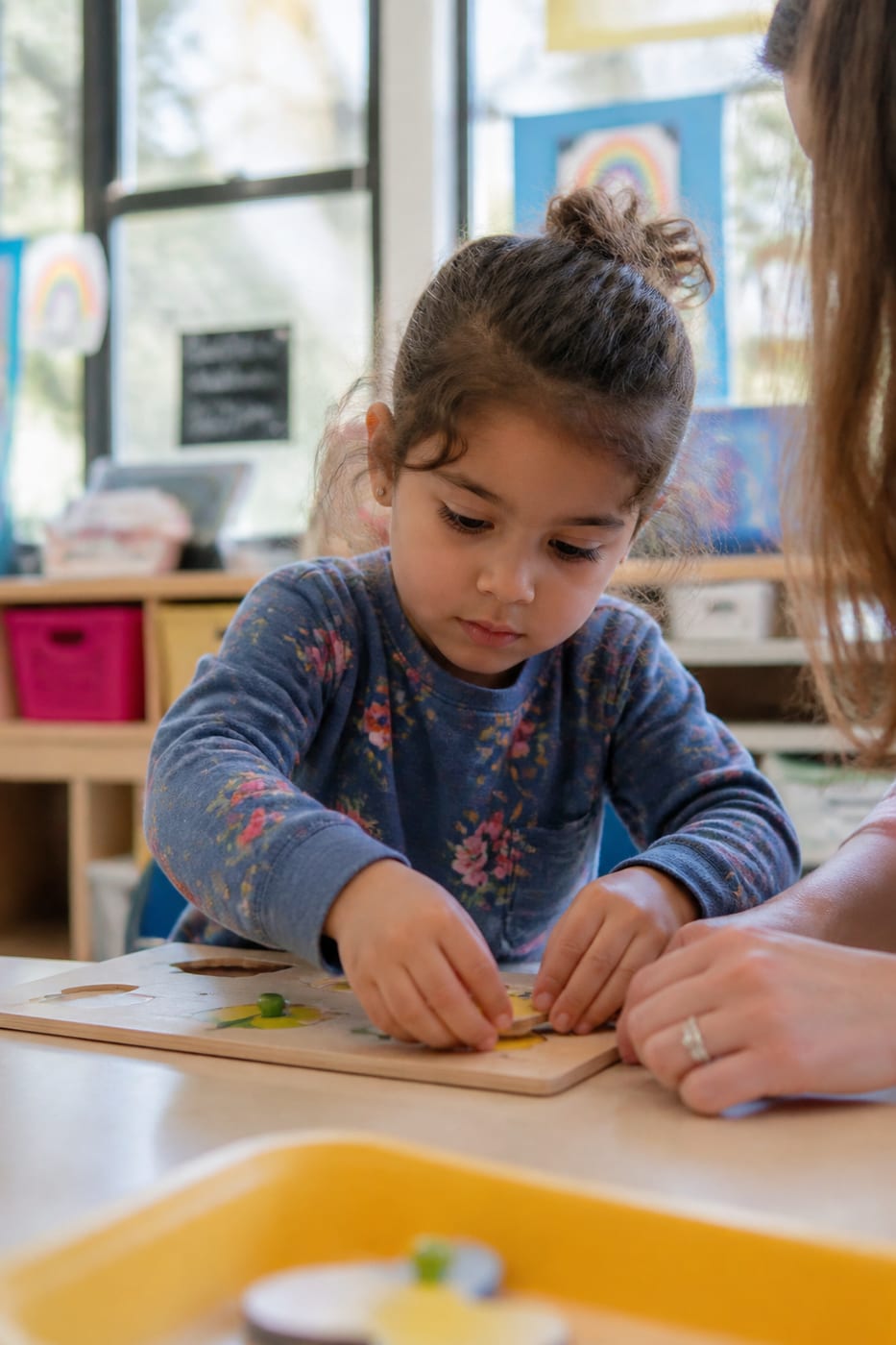 Niño concentrado con un puzzle de madera en un aula luminosa